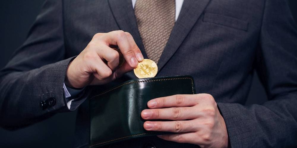 Businessmann nimmt Bitcoin aus seiner Geldbörse