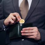 Businessmann nimmt Bitcoin aus seiner Geldbörse