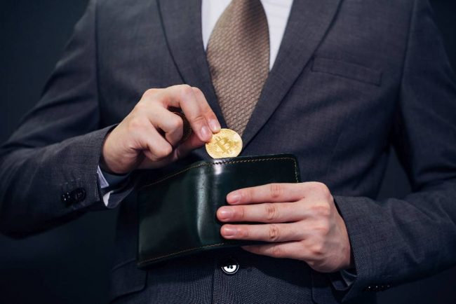 Businessmann nimmt Bitcoin aus seiner Geldbörse